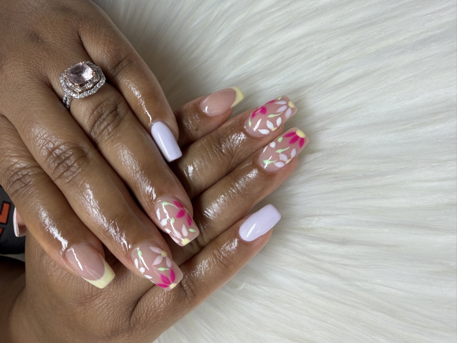 A nude gel set with hand-painted pink florals and yellow tip accents by TLC Nails and Esthetics in Nottingham, MD